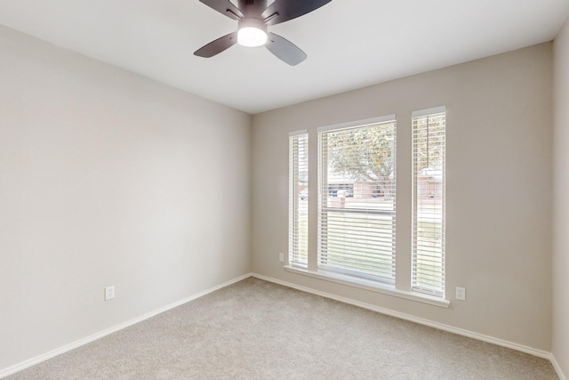 empty room featuring a ceiling fan, baseboards, and light carpet