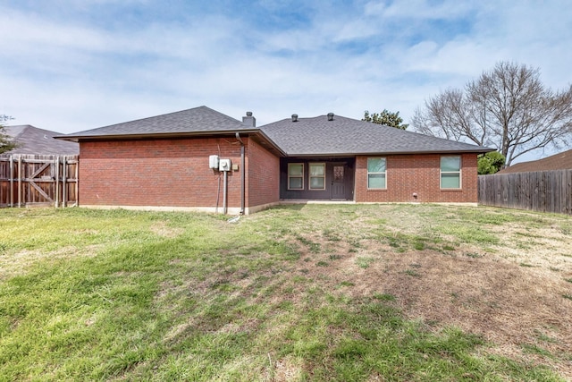 back of property featuring brick siding, a fenced backyard, and a yard