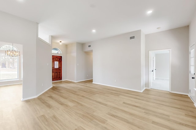 unfurnished living room featuring visible vents, baseboards, recessed lighting, light wood-style floors, and a notable chandelier