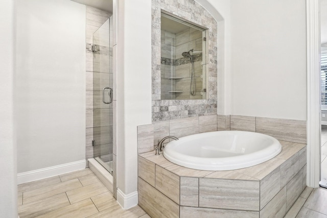 full bath with baseboards, a garden tub, and a stall shower