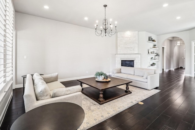 living room featuring a notable chandelier, dark wood-type flooring, recessed lighting, arched walkways, and baseboards