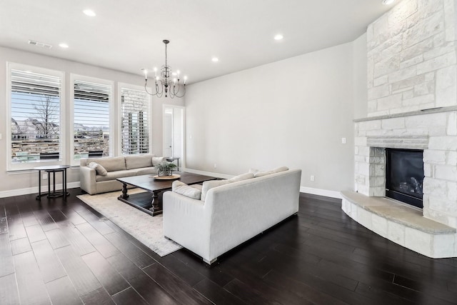 living area featuring visible vents, dark wood-style floors, an inviting chandelier, a fireplace, and baseboards