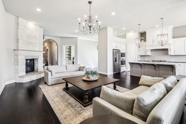 living area featuring visible vents, dark wood-style floors, an inviting chandelier, a fireplace, and baseboards