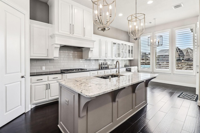 kitchen with visible vents, backsplash, a notable chandelier, white cabinetry, and a sink