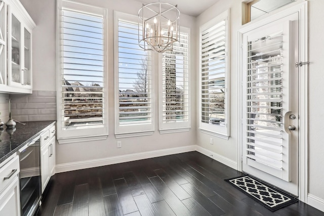 doorway to outside featuring dark wood-style floors, baseboards, and a chandelier