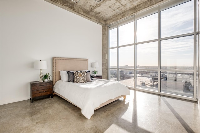 bedroom featuring access to outside, finished concrete floors, baseboards, and expansive windows