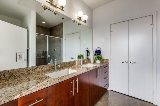 bathroom with a shower stall, double vanity, concrete floors, and a sink