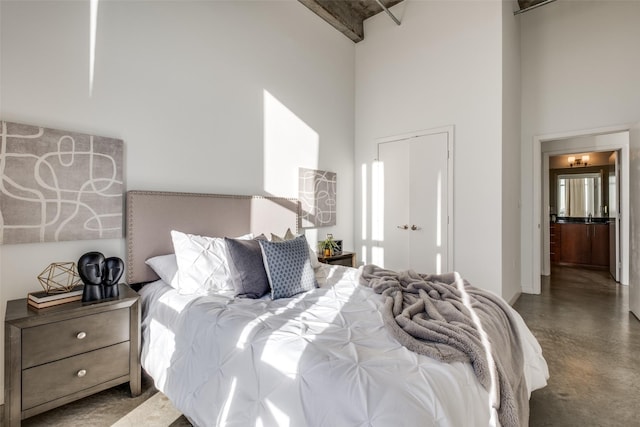 bedroom with a closet, concrete floors, and a high ceiling