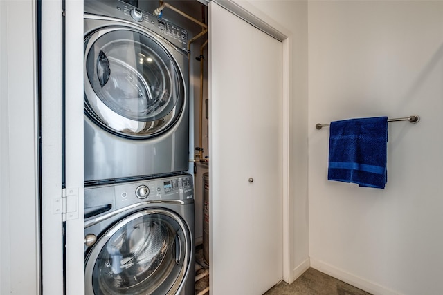 laundry room featuring baseboards, stacked washer and clothes dryer, and laundry area