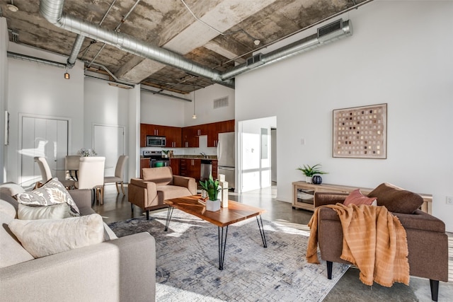 living area with visible vents, concrete flooring, and a towering ceiling