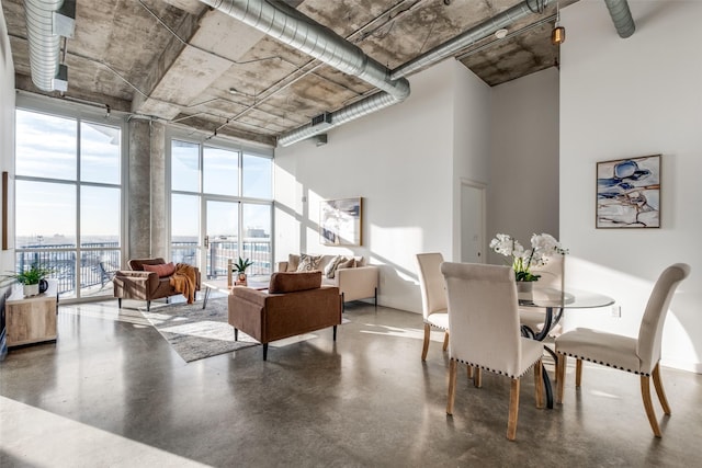 dining area with floor to ceiling windows, concrete flooring, and a high ceiling