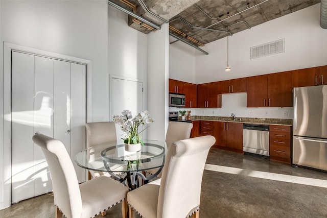 dining room with visible vents, a high ceiling, and finished concrete floors