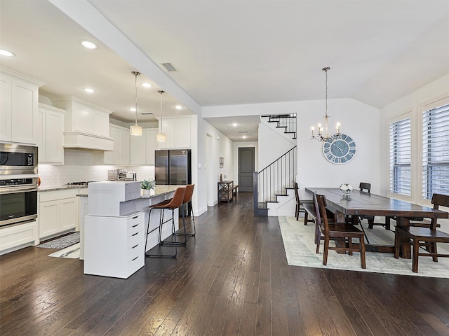 kitchen featuring visible vents, dark wood finished floors, stainless steel appliances, a kitchen bar, and backsplash