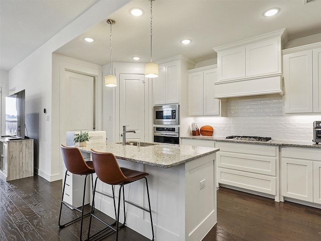 kitchen with a sink, appliances with stainless steel finishes, dark wood-style floors, and white cabinetry