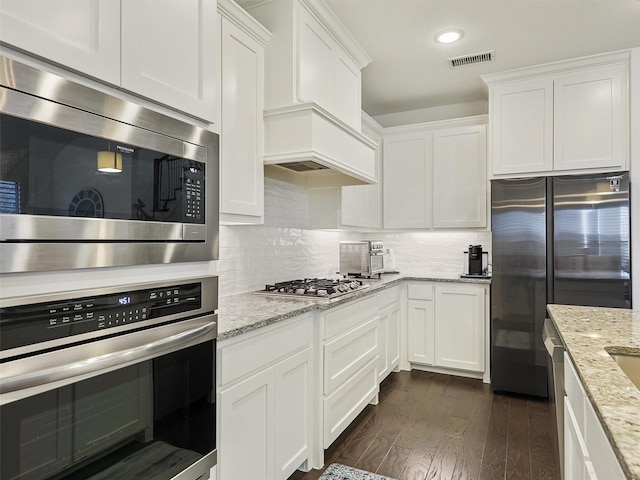 kitchen with dark wood finished floors, white cabinets, tasteful backsplash, and appliances with stainless steel finishes