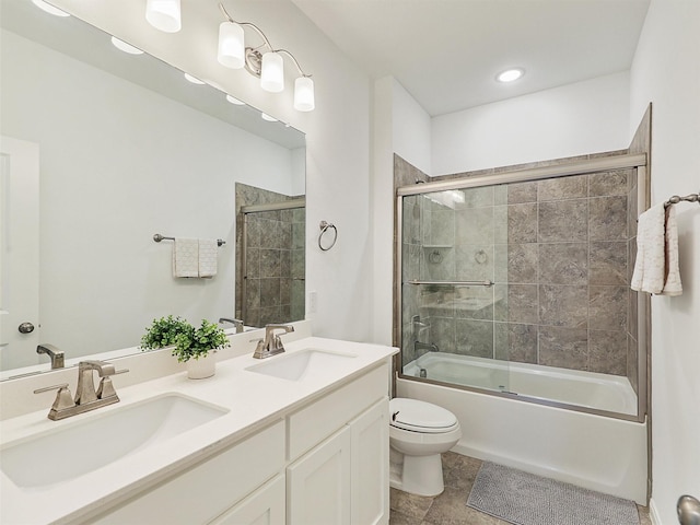 full bathroom featuring a sink, shower / bath combination with glass door, double vanity, and toilet