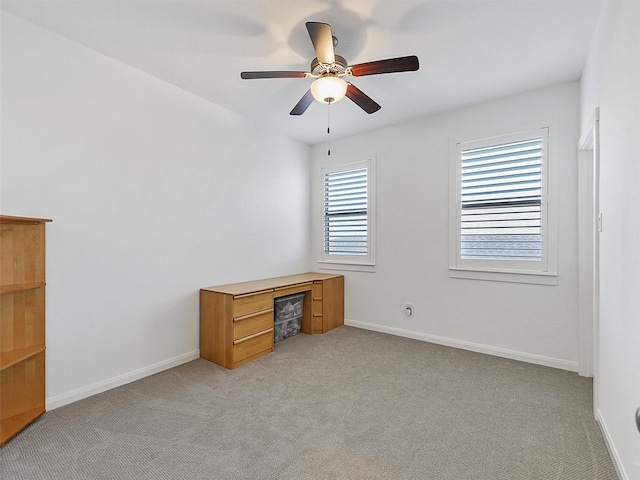 interior space featuring baseboards, light carpet, and a ceiling fan