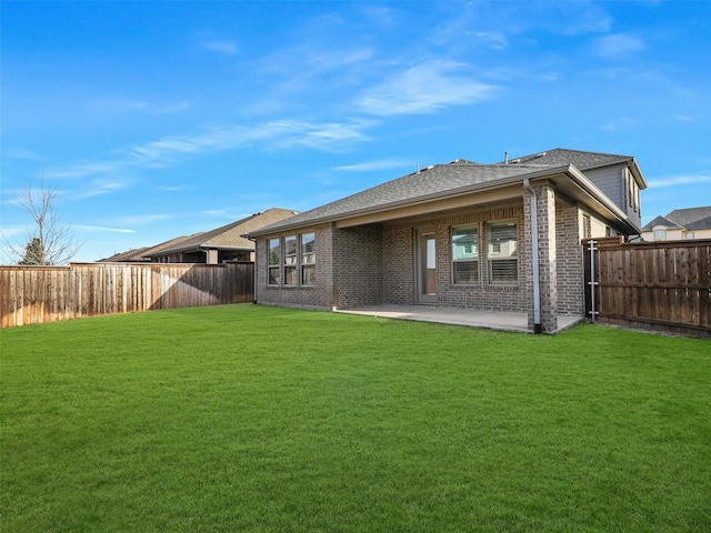 back of property with a patio area, a yard, a fenced backyard, and brick siding