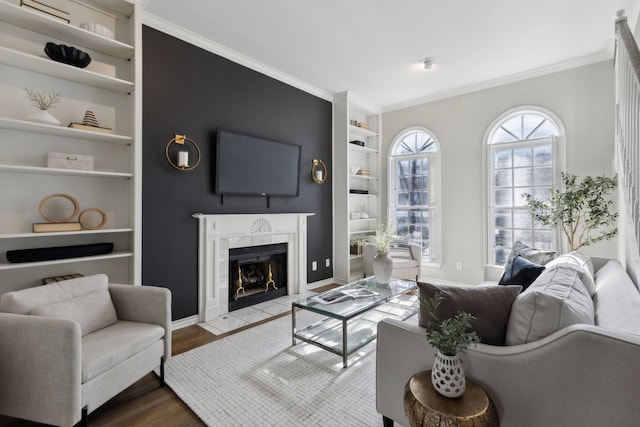 living area with built in shelves, ornamental molding, baseboards, dark wood-style flooring, and a tile fireplace