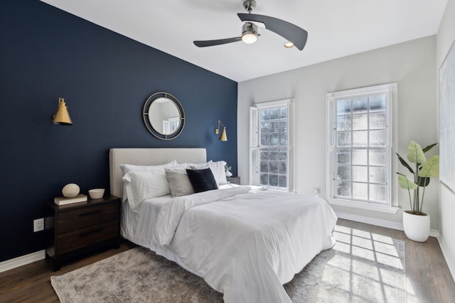 bedroom with an accent wall, baseboards, and wood finished floors