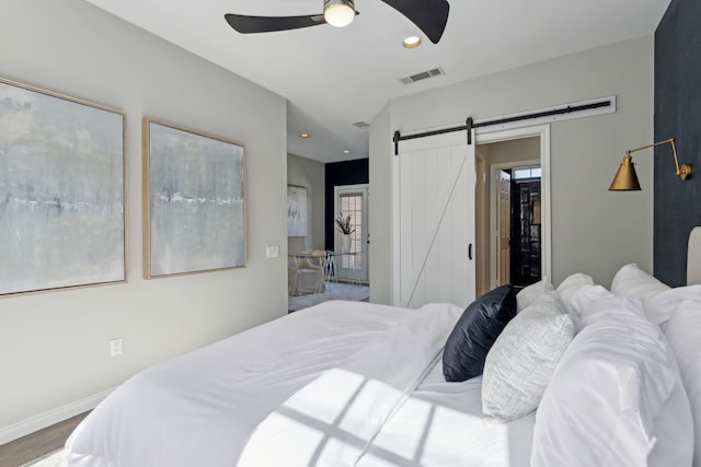 bedroom featuring visible vents, baseboards, a barn door, recessed lighting, and wood finished floors