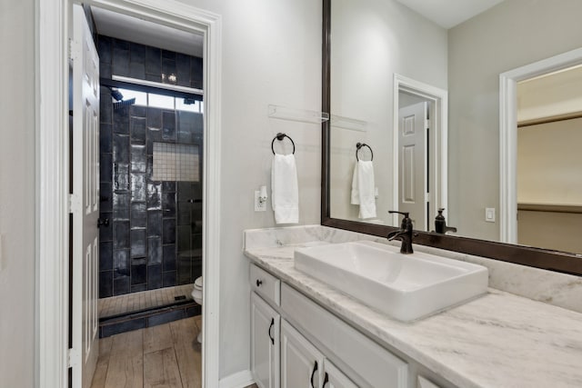 full bath with vanity, toilet, wood finished floors, and a stall shower