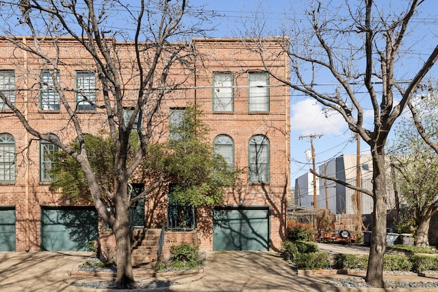 view of front facade with brick siding, an attached garage, and driveway