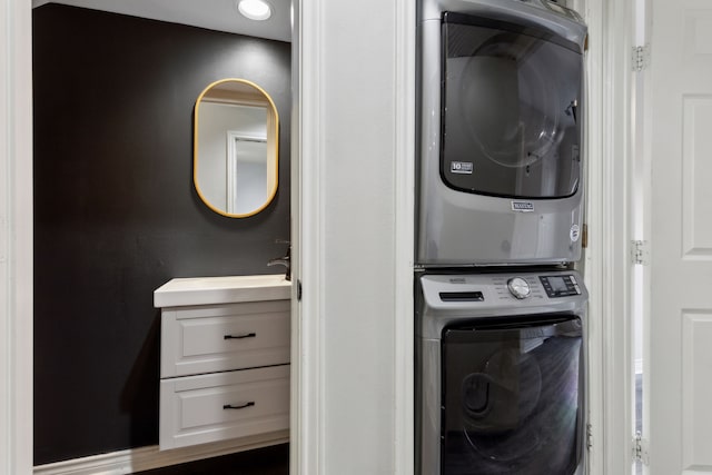 clothes washing area with a sink, stacked washer and clothes dryer, and laundry area