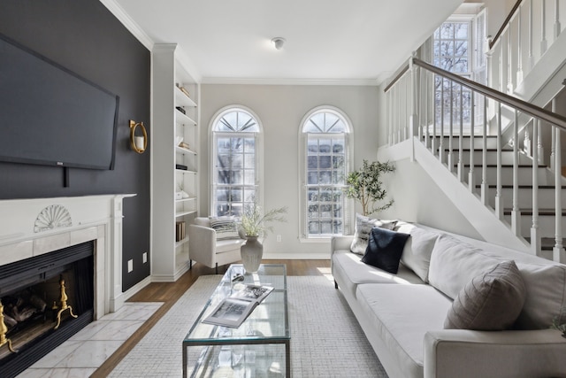 living area featuring built in features, wood finished floors, stairway, crown molding, and baseboards