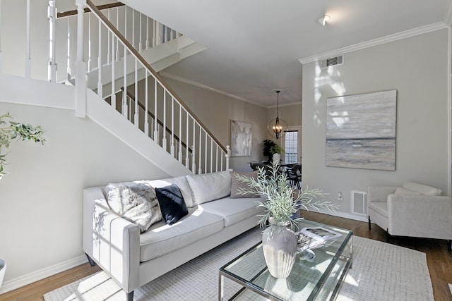 living area featuring stairway, wood finished floors, visible vents, and ornamental molding