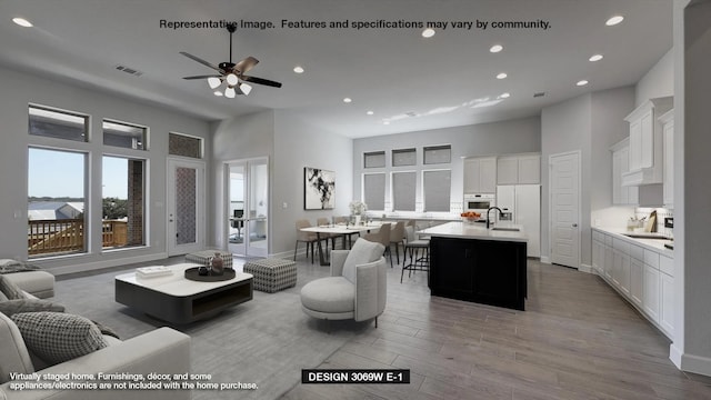 living room with visible vents, light wood-type flooring, a ceiling fan, recessed lighting, and a towering ceiling