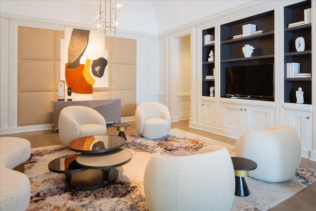 sitting room with a notable chandelier, wood finished floors, and built in shelves