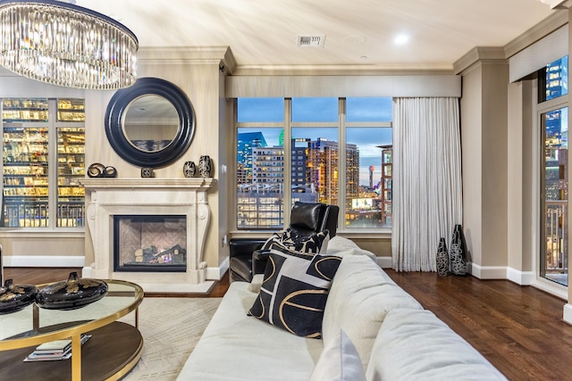 living room featuring visible vents, ornamental molding, wood finished floors, baseboards, and a chandelier