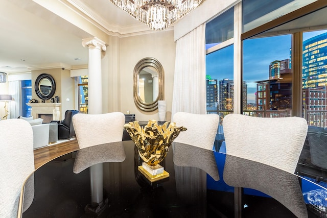 dining space with a notable chandelier, a city view, ornamental molding, a fireplace, and ornate columns