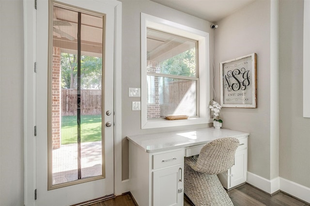 office featuring a wealth of natural light, baseboards, dark wood finished floors, and built in desk