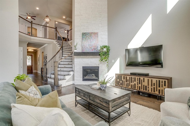 living room with stairway, wood finished floors, a high ceiling, and ceiling fan