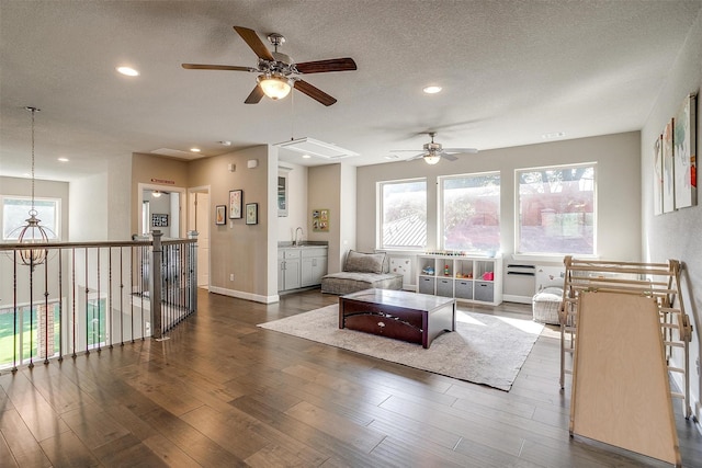 living room with baseboards, ceiling fan, recessed lighting, wood finished floors, and a textured ceiling