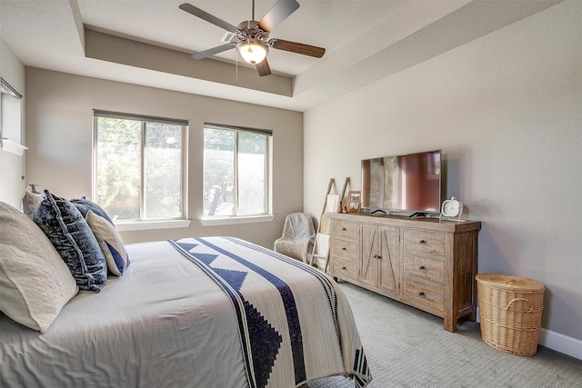 bedroom featuring light carpet, a ceiling fan, a raised ceiling, and baseboards