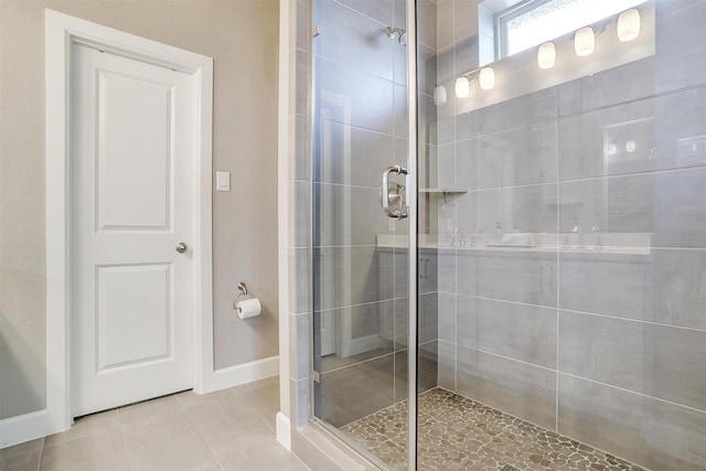 full bathroom featuring tile patterned flooring, a shower stall, and baseboards