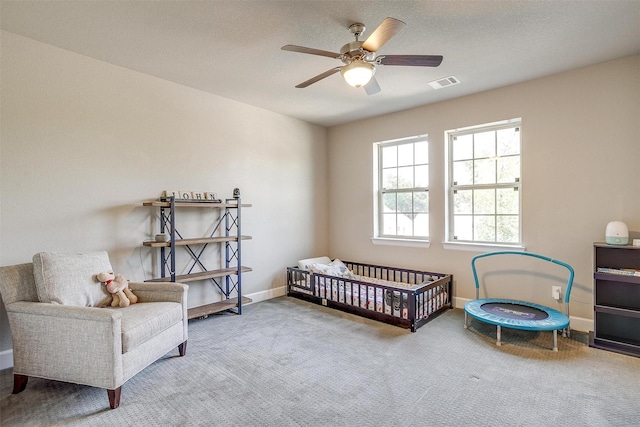 carpeted bedroom with visible vents, baseboards, a textured ceiling, and a ceiling fan