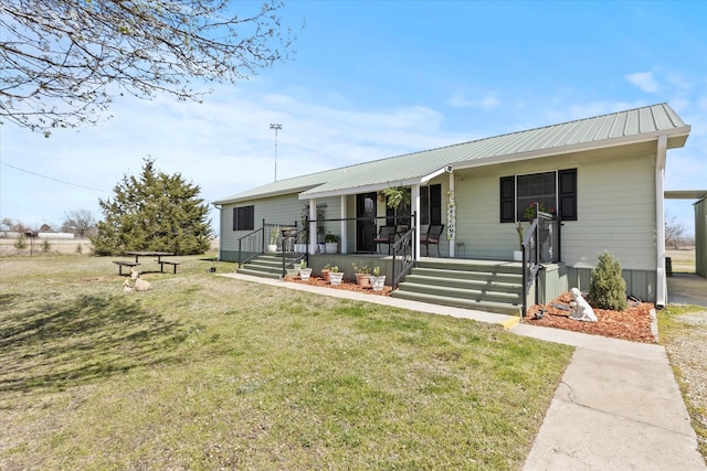 view of front of property featuring covered porch, metal roof, and a front lawn