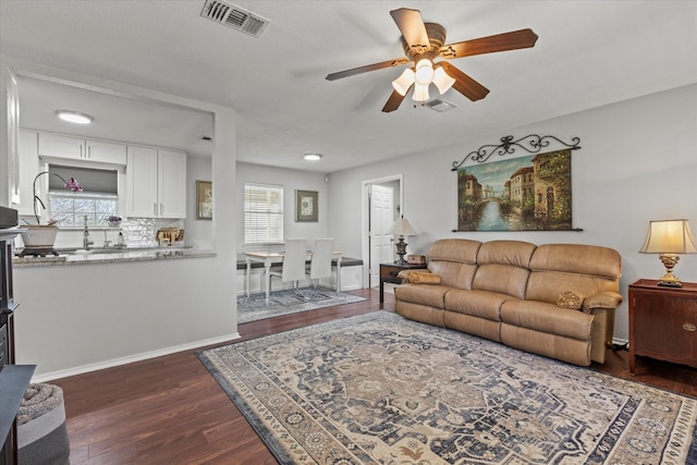 living area with dark wood finished floors, a ceiling fan, visible vents, and baseboards