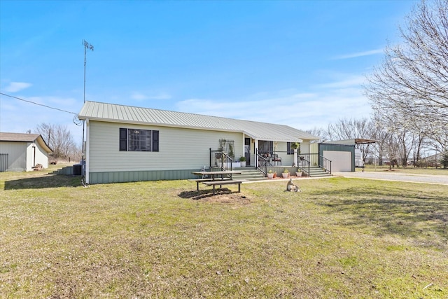 view of front of property featuring an outbuilding, a garage, driveway, cooling unit, and metal roof