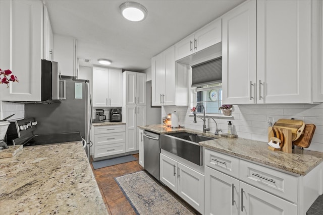 kitchen with backsplash, white cabinets, stainless steel appliances, and a sink