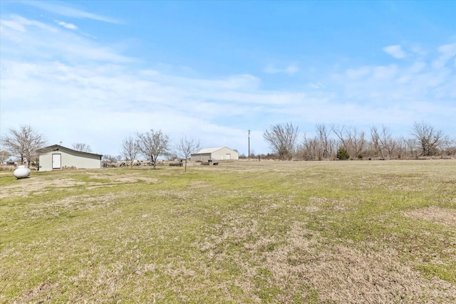 view of yard featuring an outbuilding, a pole building, and a rural view