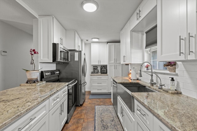 kitchen featuring decorative backsplash, white cabinets, appliances with stainless steel finishes, and a sink