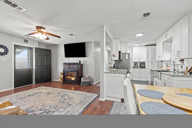 kitchen with open floor plan, visible vents, white cabinetry, and a ceiling fan