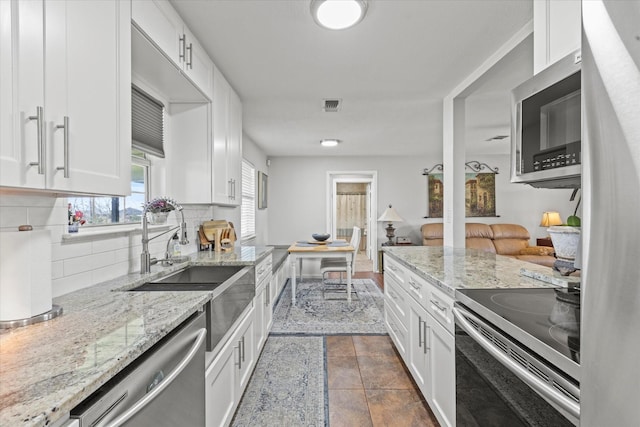 kitchen with visible vents, light stone counters, white cabinetry, appliances with stainless steel finishes, and decorative backsplash