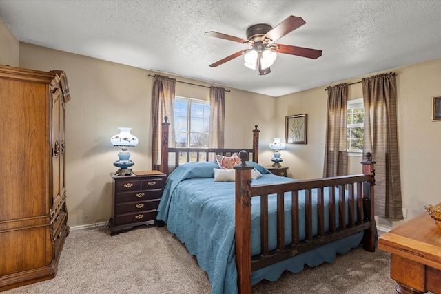 bedroom featuring light carpet, multiple windows, a textured ceiling, and a ceiling fan