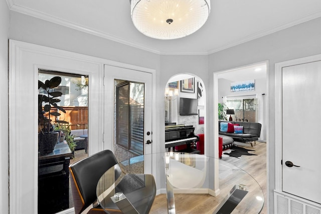 home office featuring crown molding, light wood-style floors, and arched walkways